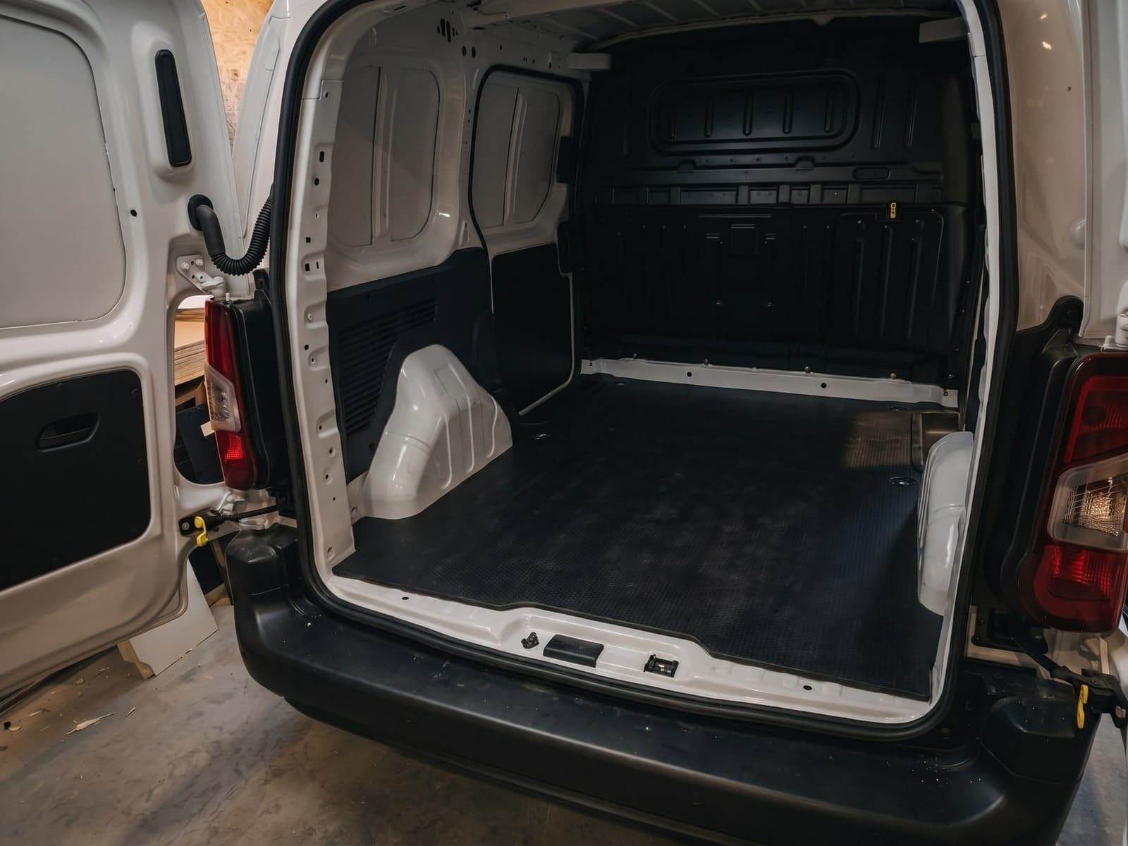 Petit fourgon utilitaire vide avant aménagement, parois nues et tapis d'origine