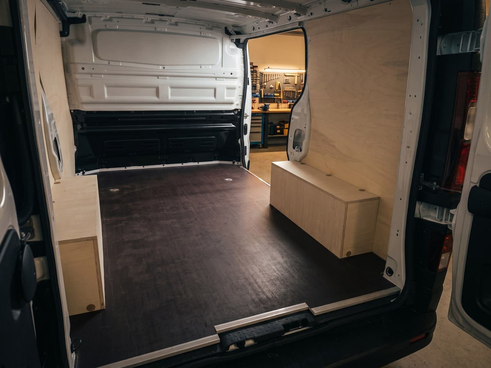 Fourgon habillé bois dans l'atelier AMB : établi et panneau d'outils en arrière-plan